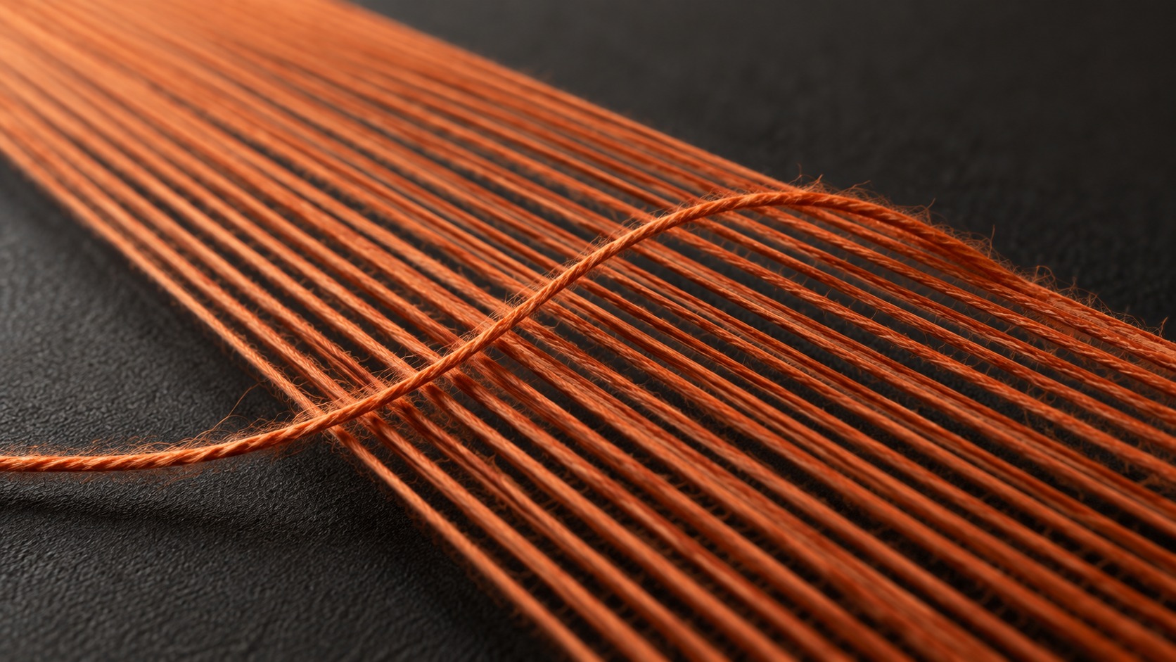 Concept macro image of orange textile threads crossing a graphite background